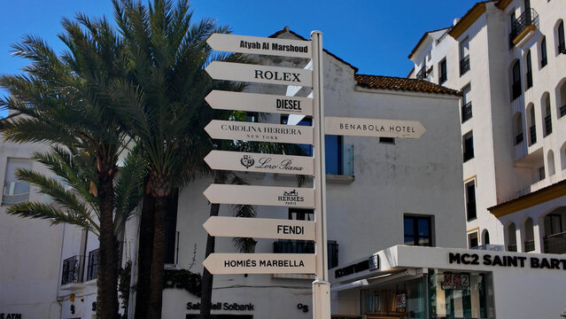Luxury shopping street signs in Marbella, Spain, featuring Rolex, Diesel, and other high end brands - MARBELLA, SPAIN - MARCH 30, 2025