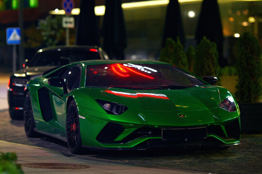 Minsk, Belarus. Sep 14, 2021. Green Lamborghini Aventador S coupe parked near Doubletree by Hilton in Minsk at night, sleek curves, luxury design, and city lights in urban scene. Grainy image