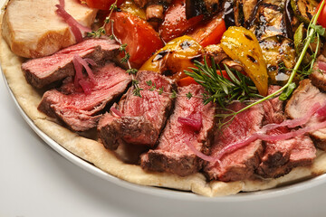Sliced grilled beef tenderloin with grilled vegetables and pita bread