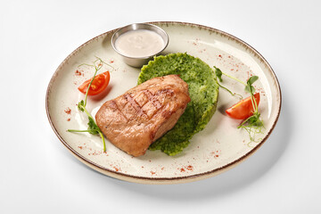 Grilled chicken breast with green puree and cherry tomatoes on elegant plate