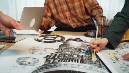 A dynamic team of engineers engages in a detailed brainstorming session, working on technical drawings and sketches of machinery in a modern office environment. SACTR