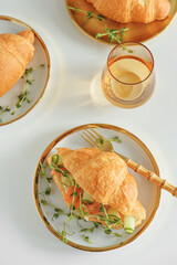 Croissant sandwich with salmon, onions and microgreens on white table. Healthy breakfast. Top view