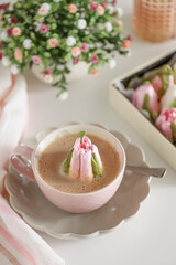 Hot chocolate in pink mug with whipped cream and tulip flower shaped marshmallows.