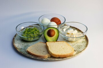 Healthy meal consisting of toast, avocado and boiled eggs arranged on a plate