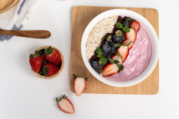 Presented by fruits putting yogurt toppings with strawberry, berry, oats, raisins and chia seed decorated by peppermint in white blow. Pink background. Set of healthy dairy product choice. Pecuniary.