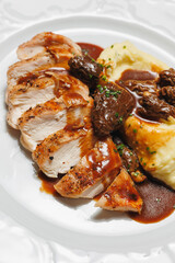 Mashed potatoes with sliced ​​steak and sauce in a white plate