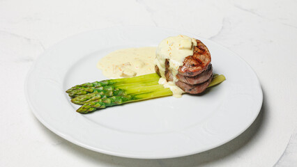 Beef medallion with asparagus and cheese sauce. Restaurant food presentation, beautiful serving.