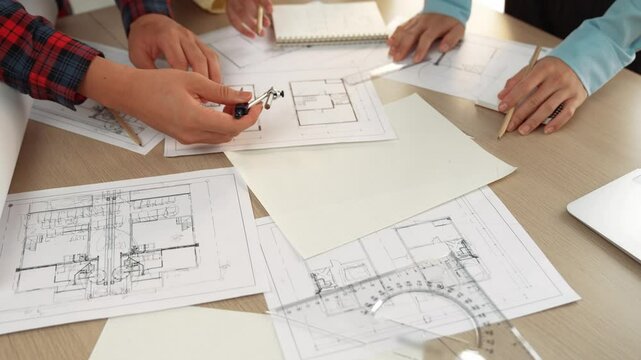 Video of architects or smart engineers use measurement tool, divider and pencil hand writing detail on blueprint for construction accuracy at architectural office. Focus on hand. Closeup. Delineation.