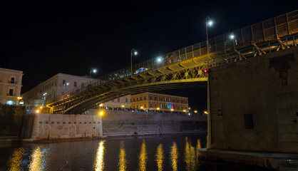 Fototapeta premium Taranto Swing Bridge Illuminated at Night with Reflections on Canal Waters