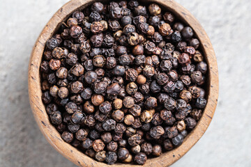 Indian spice black pepper in wooden bowl close-up on gray background macro shot. Hot spices. Herbal alternative Ayurvedic medicine. 
