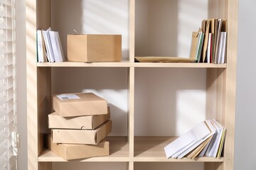 Different paper envelopes and parcels on wooden shelves in post office