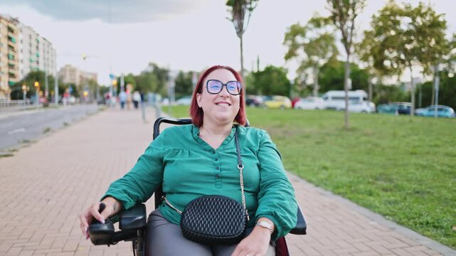 Happy disabled woman enjoying a ride in her electric wheelchair in a city park