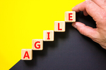 Agile symbol. Concept word Agile on beautiful wooden blocks. Beautiful yellow and black background. Businessman hand. Business agile concept. Copy space.