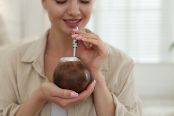 Woman with traditional yerba mate tea at home, closeup