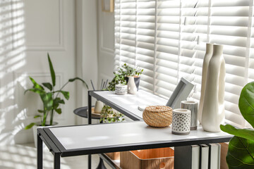 Console table with different decor near window indoors. Interior design