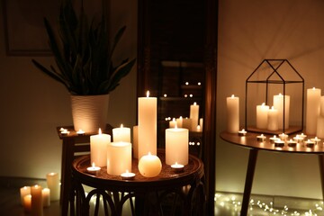Many burning paraffin candles in dark room