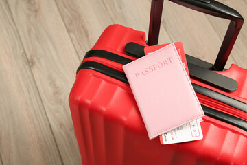Passport with ticket and red suitcase on floor, closeup. Space for text