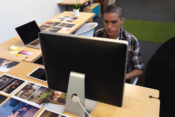 Young adult man reviewing printed photos and swatches at modern studio desk, copy space
