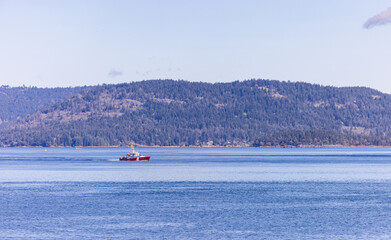 Obraz premium Red Boat Sailing in Calm Waters Near Forested Gulf Islands in BC Canada