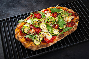 Traditional Italian pinsa bread prosciutto e salsa di pomodoro with tomatoes and zucchini in tomato...