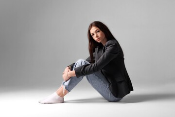 Fashion model sits gracefully against a minimalist backdrop, showcasing a modern look during a...