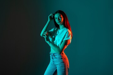 Model poses creatively under colorful lighting in a studio setting during a fashion photoshoot