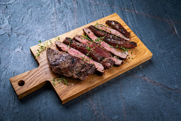 Barbecue grilled dry aged meat wagyu beef flank steak cut as tagliata on wooden board with text space