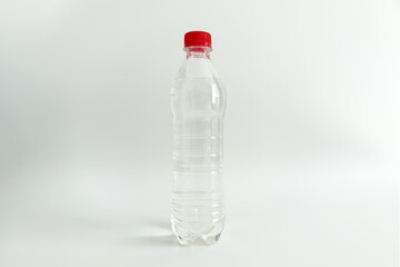 Clear plastic bottle filled with water featuring with red cap against plain background