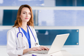 Pretty young female woman doctor nurse in lab coat with stethoscope in hospital clinic working on laptop computer