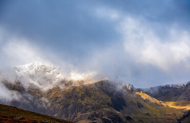Shifting mist blankets Cwm Idwal in the Glyderau, unveiling fleeting glimpses of soaring Welsh summits crowned by subtle snow