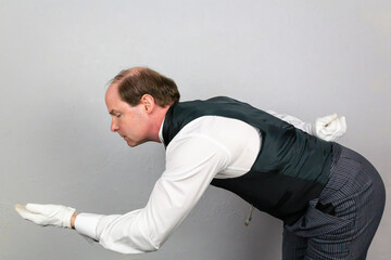 Butler in Formal Attire and White Gloves Bowing in Polite Greeting and Offering a Helping Hand. Professional Hospitality and Service.