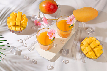 Cold homemade lemonade cocktail, juice or smoothie with mango, ice and fruits on sunny table,...