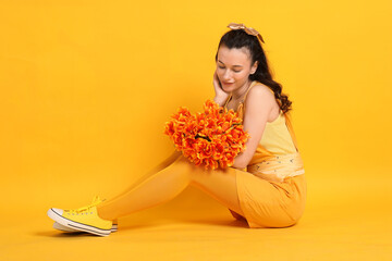 Smiling woman with bouquet of beautiful tulips on yellow background