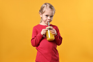 Girl drinking tasty juice on orange background. Refreshing drink