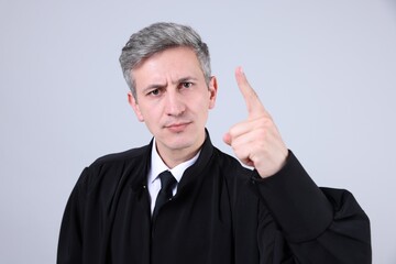 Portrait of judge shaking finger on grey background