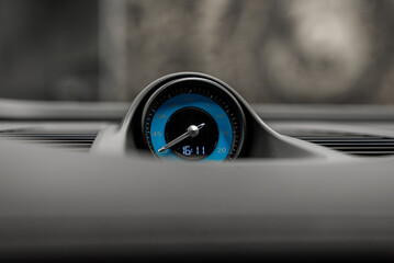 A detailed view of a blue and black analog clock with silver hands and a digital display reading 16 11, set in a sleek luxury car dashboard.