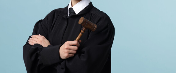 Judge with mallet on light blue background, closeup