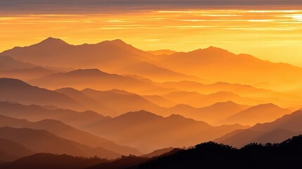 Obraz premium Majestic mountain range at sunrise with golden light illuminating misty peaks