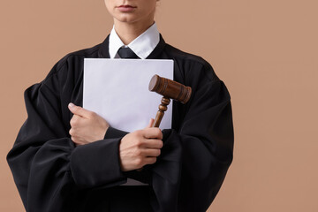 Judge with mallet and documents on light brown background, closeup