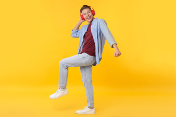 Happy man in headphones dancing on yellow background