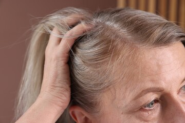 Fototapeta premium Senior woman with healthy hair roots on blurred background, closeup