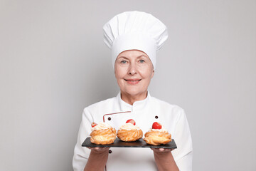 Professional pastry chef with choux on light grey background