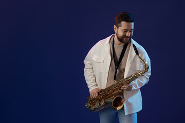 Professional musician with saxophone on blue background. Space for text
