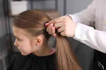 Naklejka premium Hairdresser doing girl's hairstyle in salon, closeup