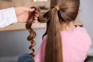 Fototapeta premium Hairdresser doing girl's hairstyle in salon, closeup