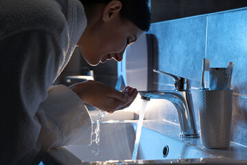 Woman washing her face over sink in bathroom