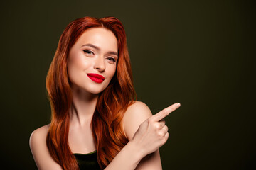 Obraz premium Photo of tender gentle stunning rich lady pointing finger empty space isolated on khaki color background