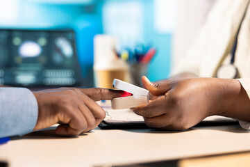 General practitioner takes the oxygen saturation measurements and pulse rate using an oximeter during checkup, consulting young man with modern medical equipment. Oxygen levels indicator.