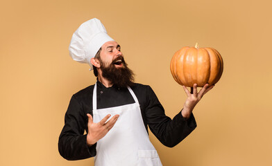 Restaurant menu. Happy bearded man in chef hat and uniform with pumpkin. Male chef, cook, baker in apron with pumpkin for culinary. Harvest festival. Seasonal vitamin. Useful vegetables. Organic food.