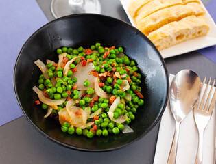Appetizing dish of green peas with ham, cooked with onions and chopped pepper